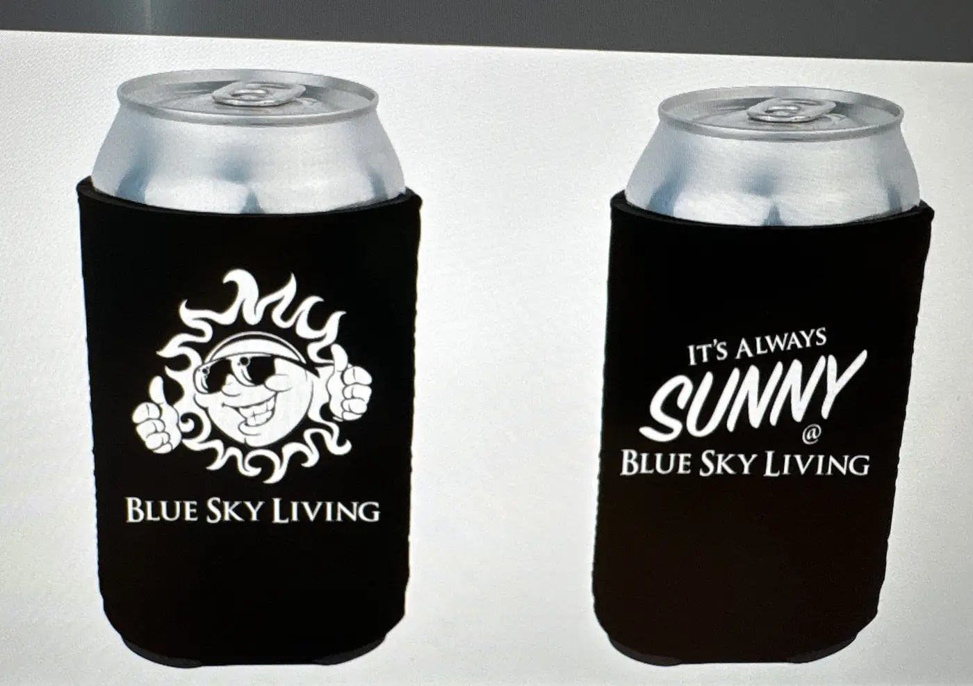 Two black can koozies, one with the sun logo and one with the tagline